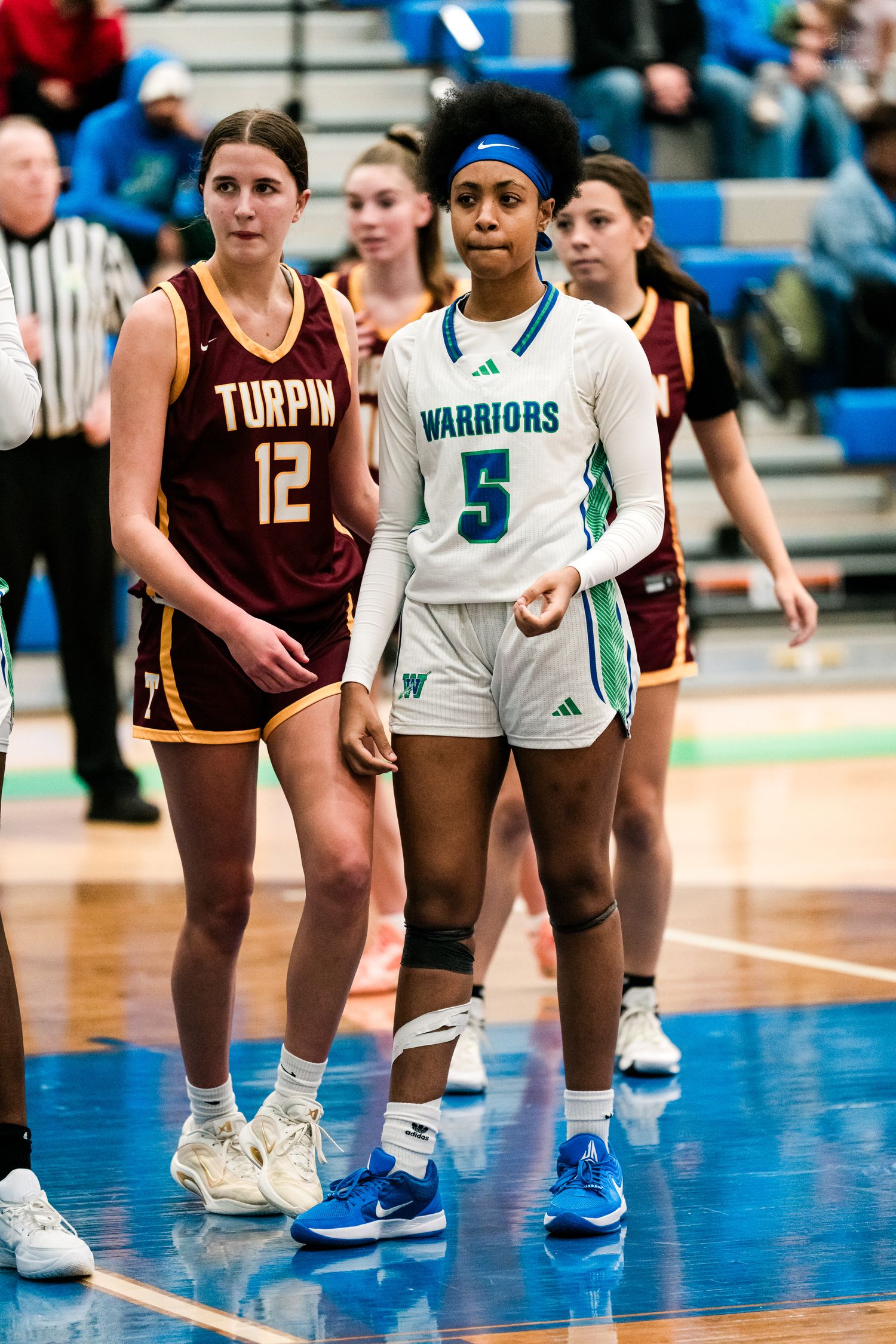 Warriors #5 and Turpin #12 stand together during a stoppage in a girls high school basketball game.