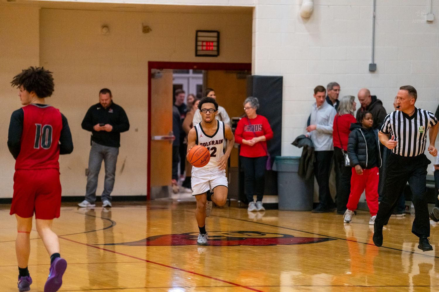 A Colerain basketball player dribbles upcourt past defenders during a high school basketball game.
