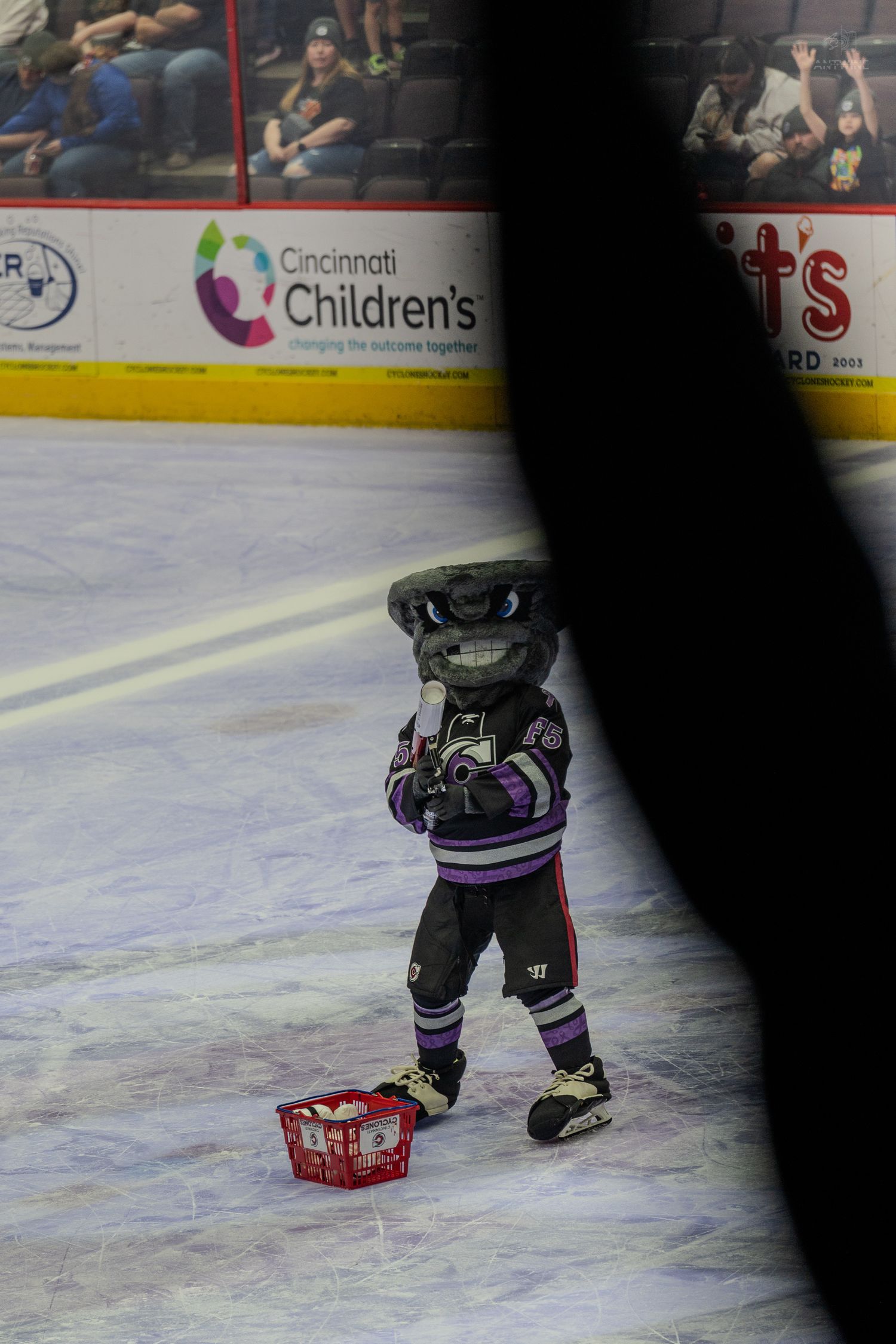 Cincinnati Cyclones mascot on ice rink near Cincinnati Childrens arena advertisement.
