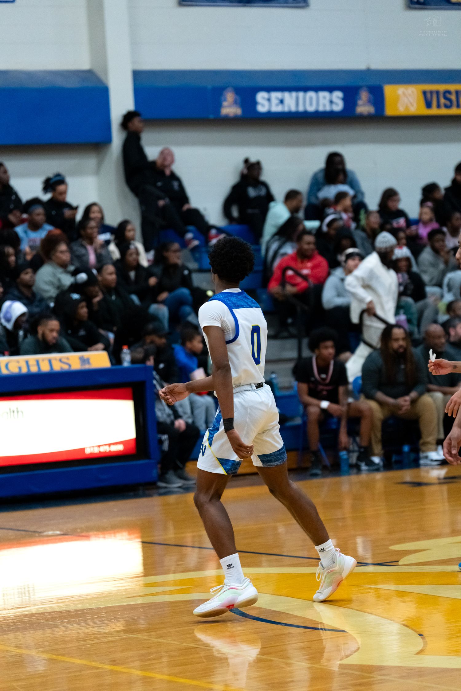 Player #0 in blue and white uniform runs on basketball court.