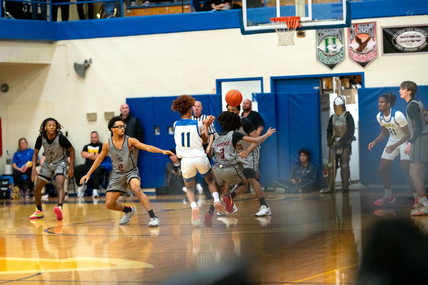High school basketball player number 11 drives toward the basket while defenders attempt to block the shot.