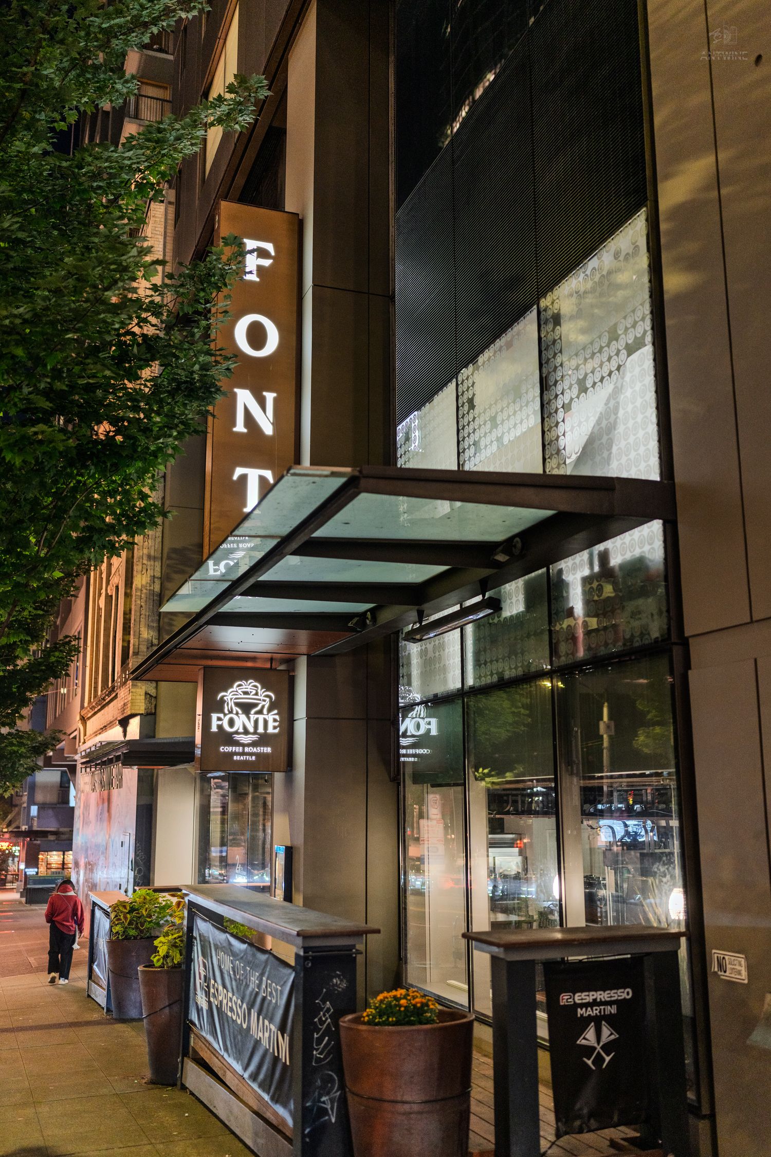 Fonte coffee shop exterior at night with illuminated vertical sign and glass canopy entrance in downtown Seattle.