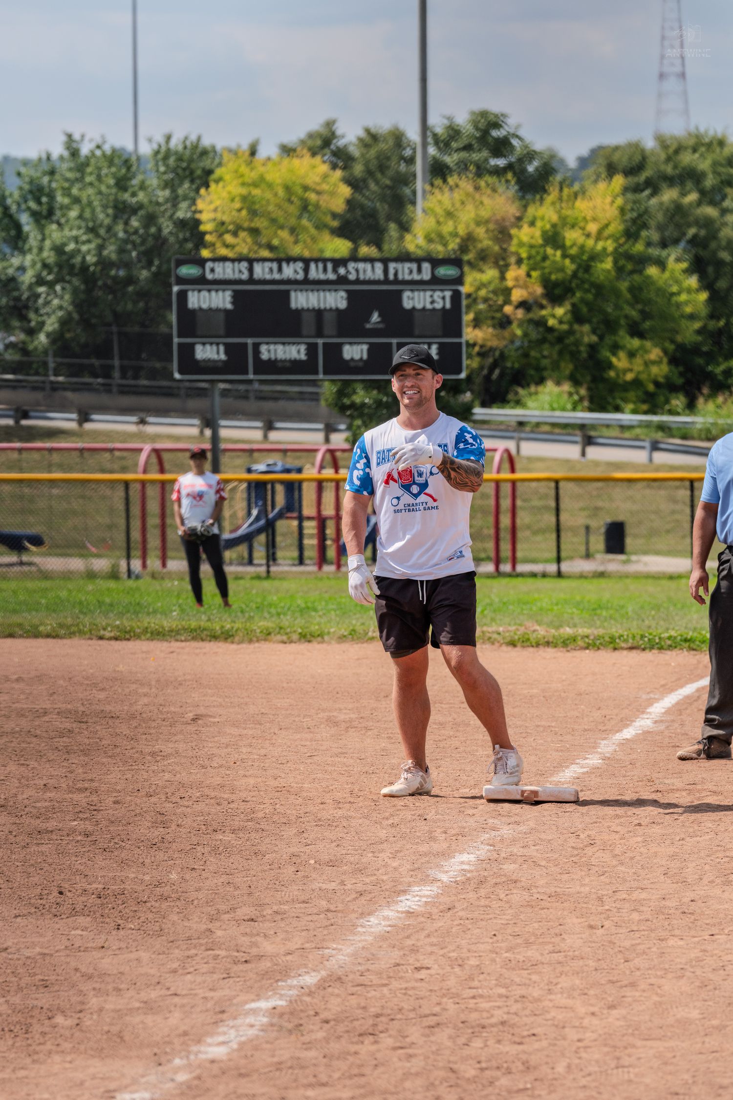 Male softball player standing on base at Chris Helms All-Star Field during outdoor charity game.