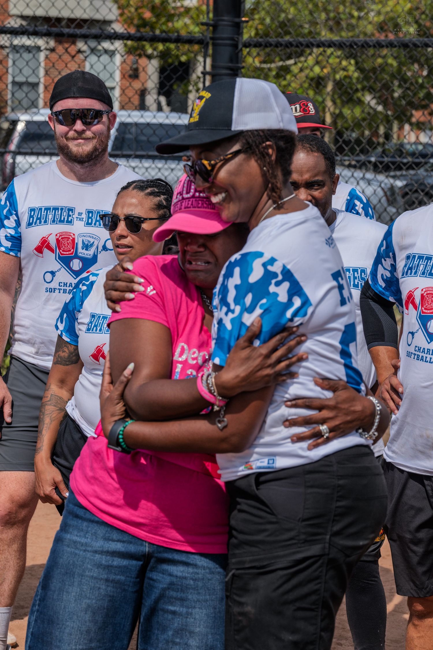 Two women share a heartfelt hug at a Battle of the Badges charity softball game event.