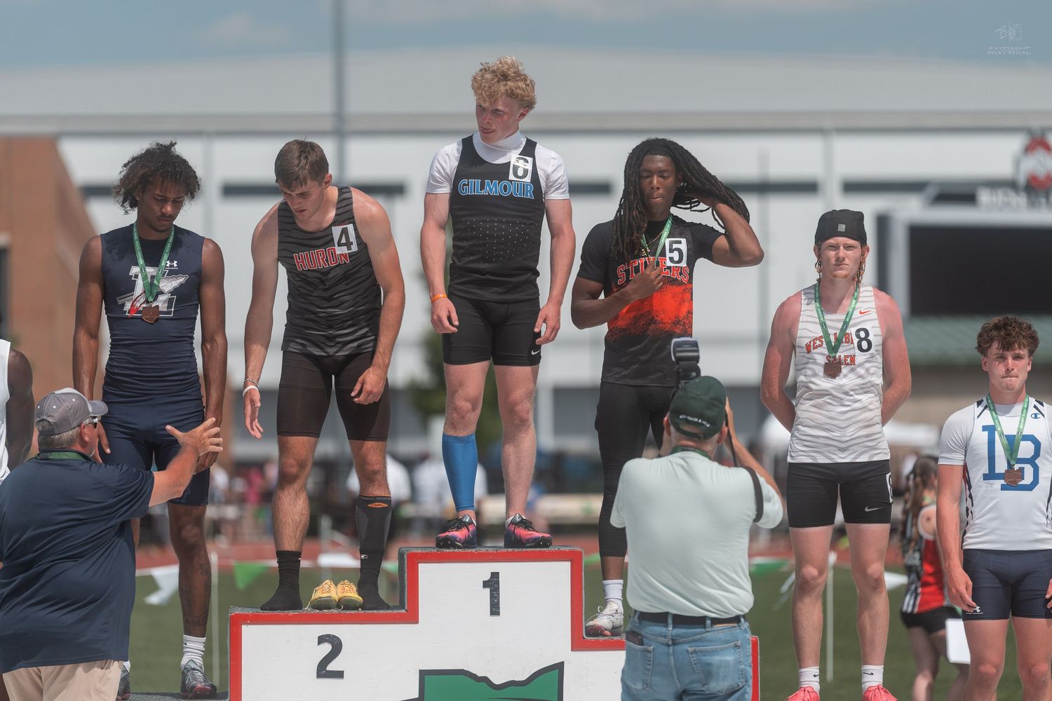 High school male sprinters receive medals on podium at OHSAA track and field championship event.