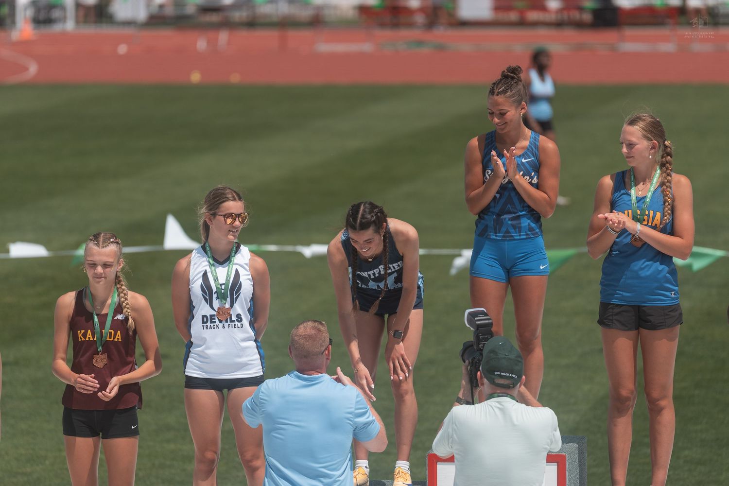 Girls track and field athletes stand on award podium at OHSAA state championship long jump competition.