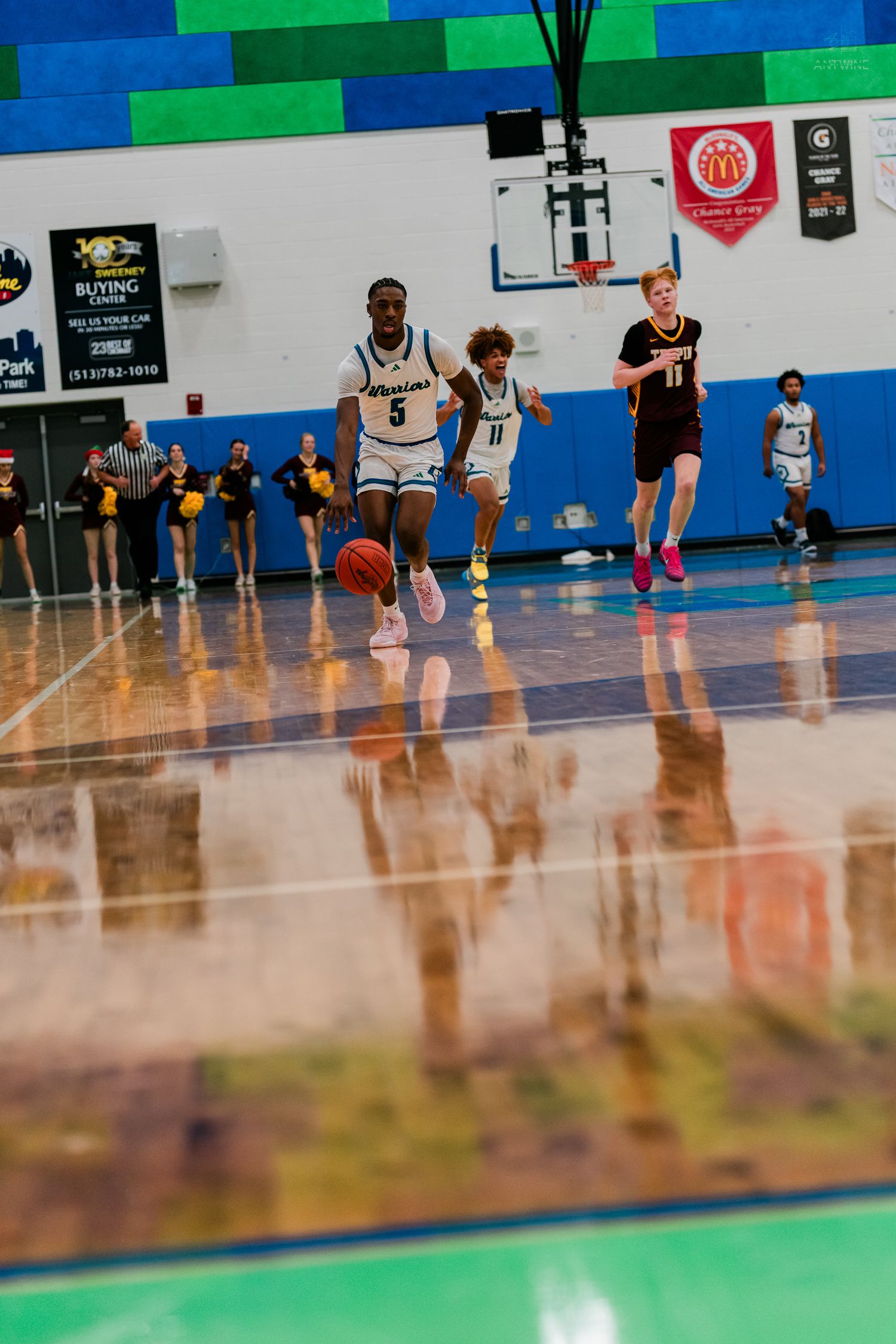 Warriors player number 5 dribbles fast on a fast break during a high school basketball game.
