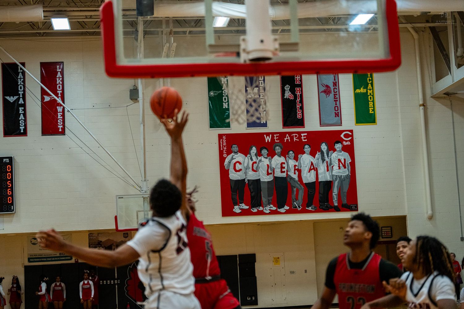 Basketball player attempts a layup shot during a high school game in a decorated gym.