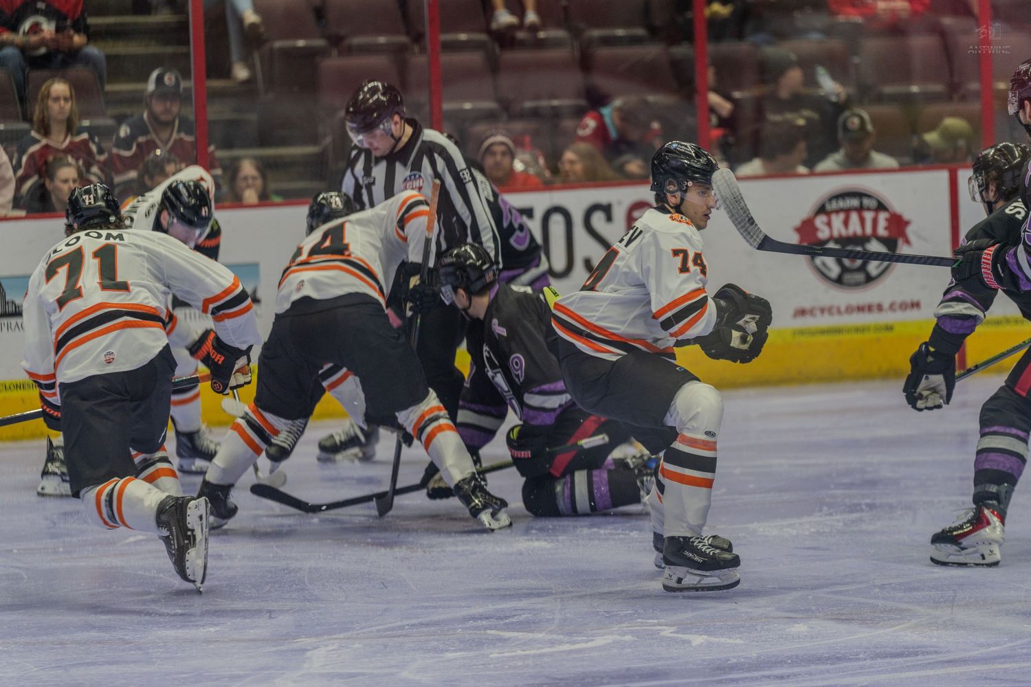 Referee oversees an intense puck battle between players during a hockey game.