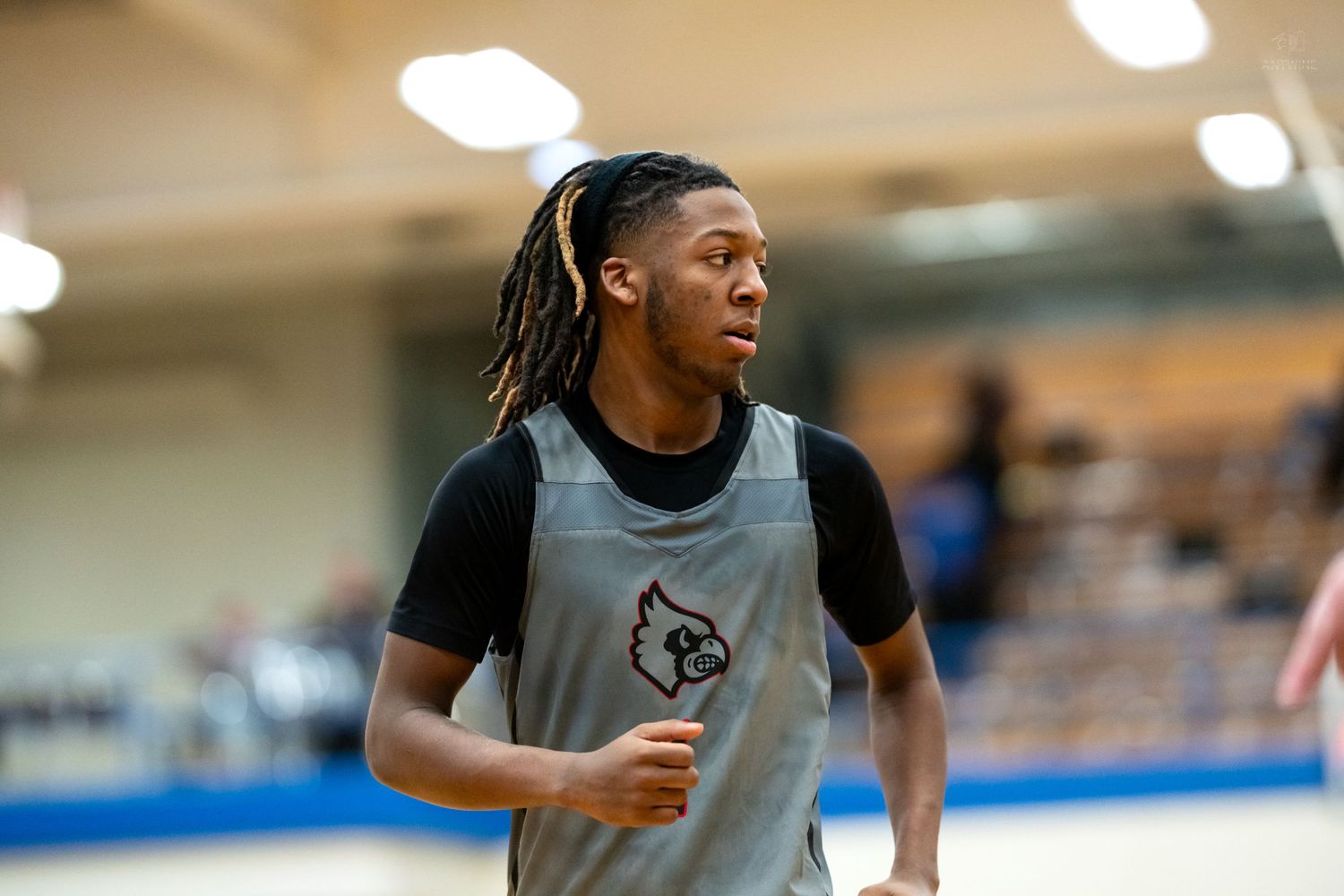 Young basketball player in gray Cardinals scrimmage vest jogs during practice warmups.