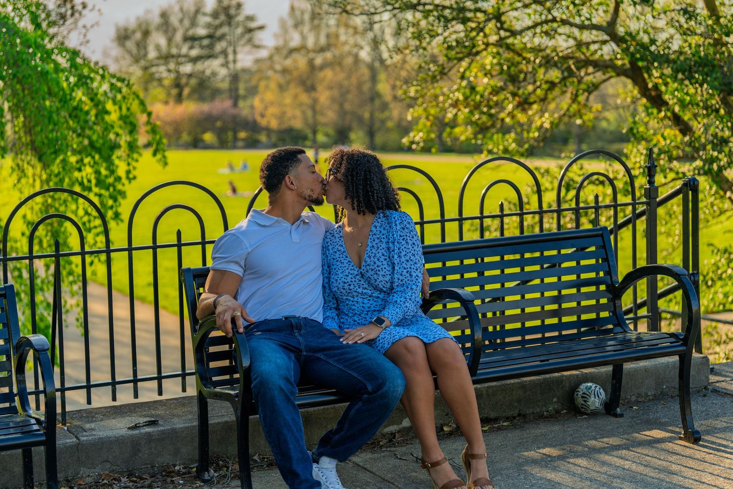 Romantic couple leaning in for a kiss on a park bench in golden sunlight.
