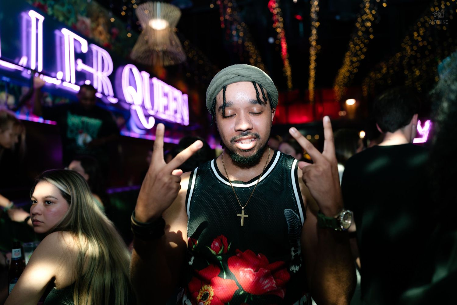 Young man posing with peace signs at Killer Queen bar nightclub party.
