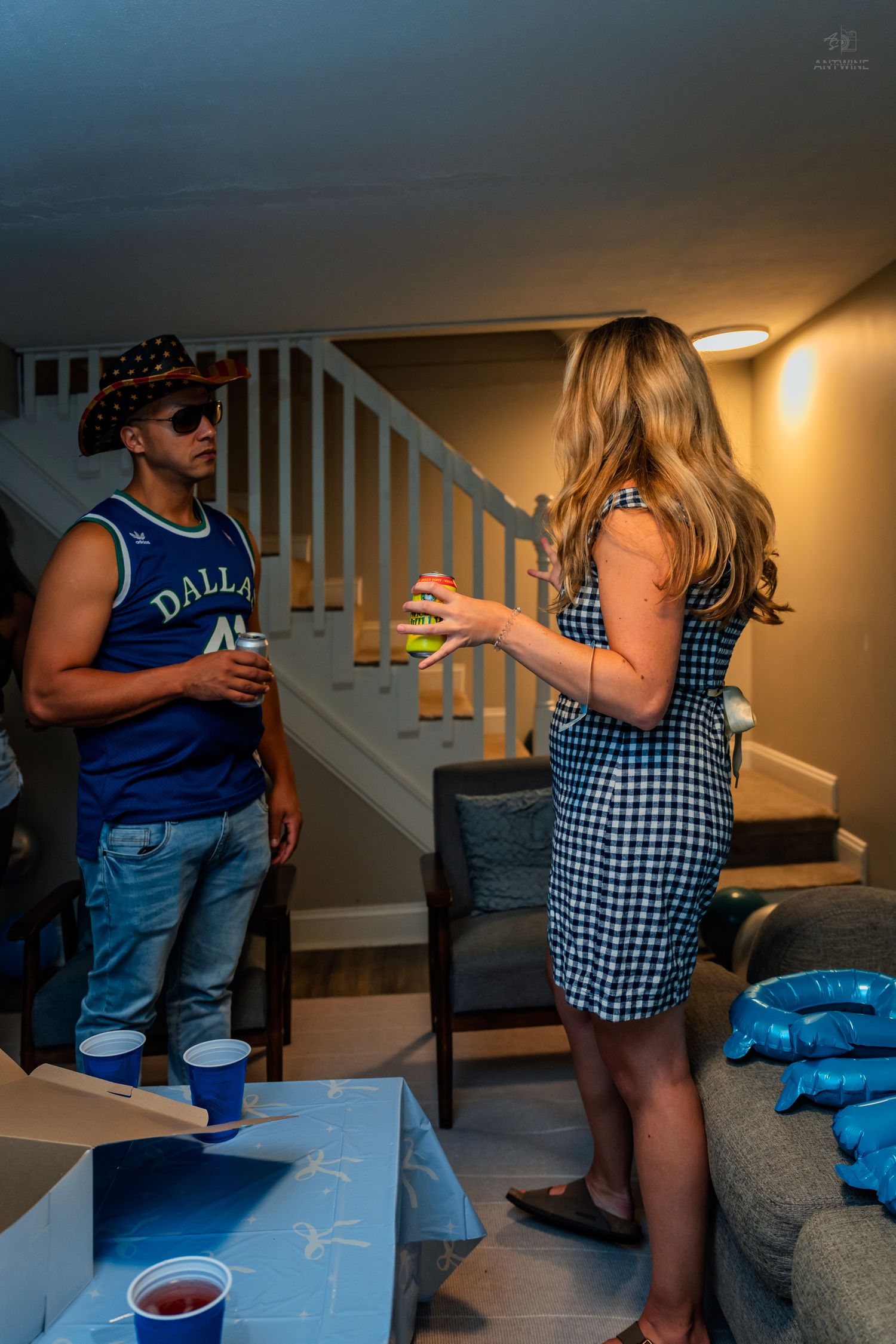 Two guests chat near a beer pong table at an indoor birthday party.