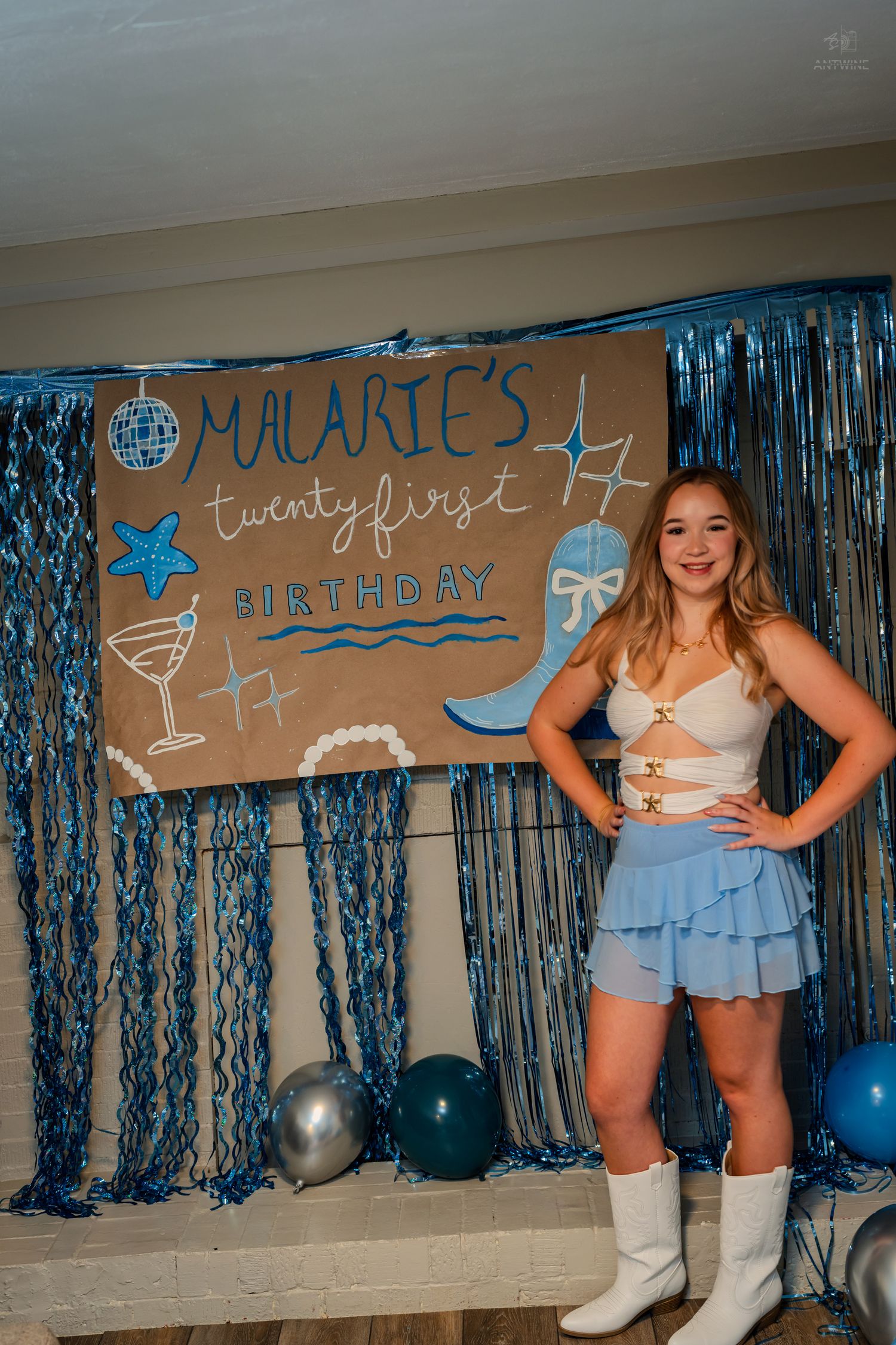 Smiling birthday girl in white boots and blue skirt posing at Malarie's 21st birthday celebration.