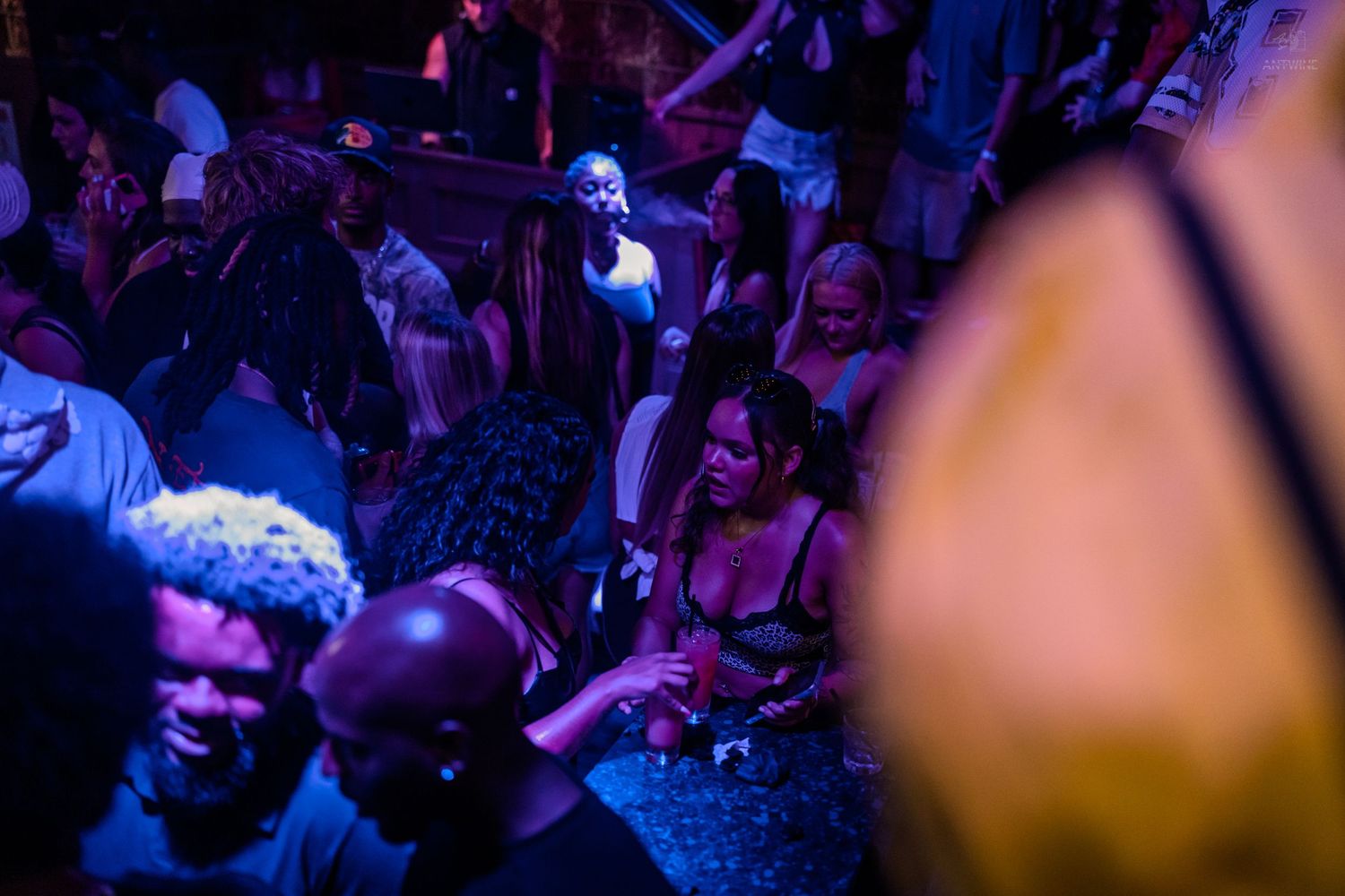People dancing under blue neon lights at a crowded nightclub party.