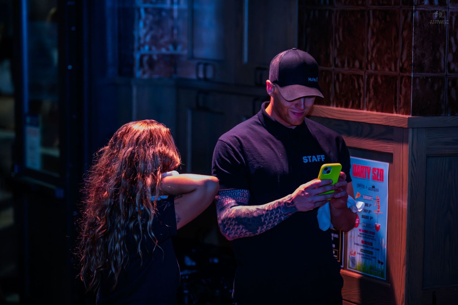 Tattooed staff member scanning a ticket at a nightclub entrance.