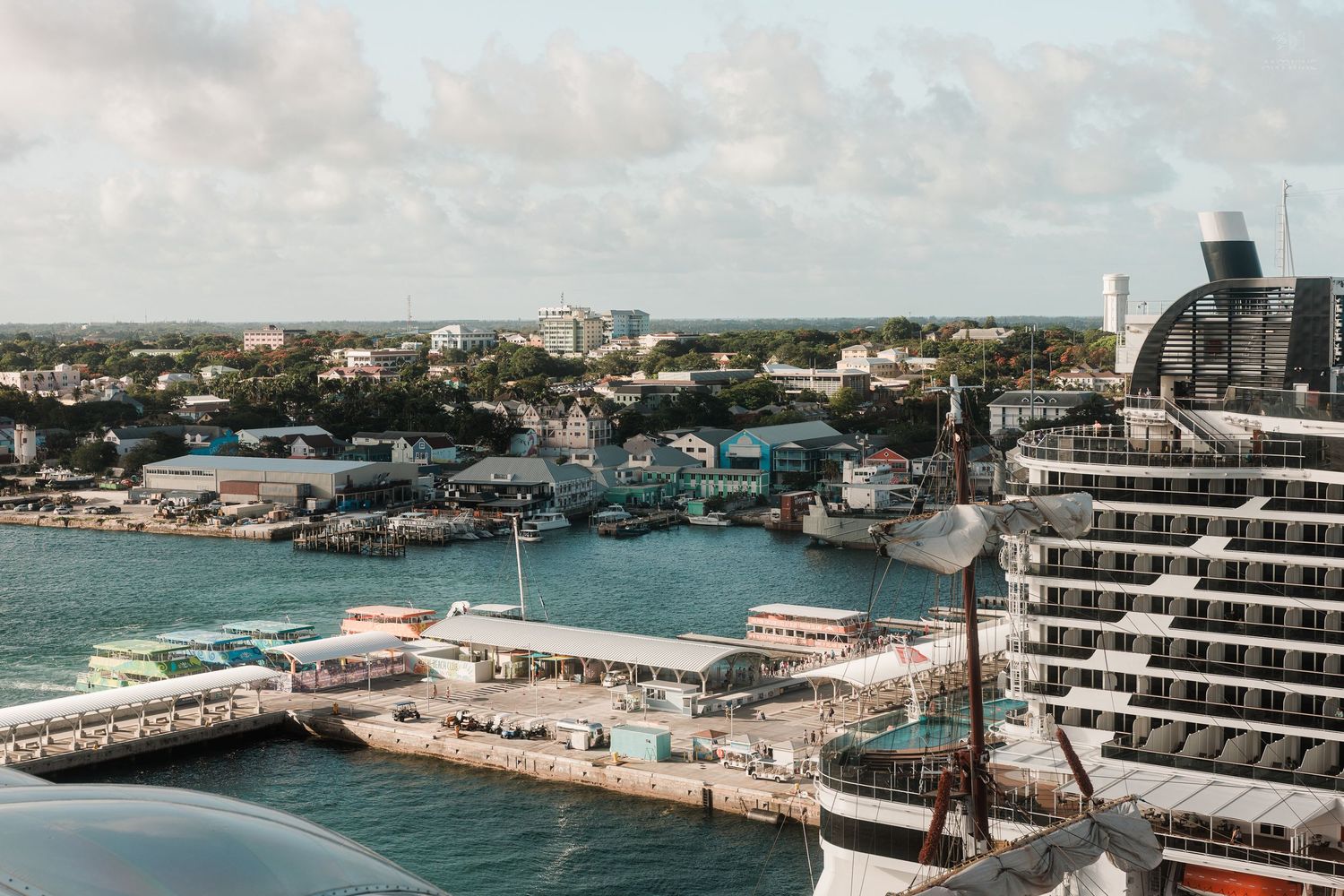 Aerial view of a busy Caribbean cruise port with ships docked along the waterfront and city buildings beyond.