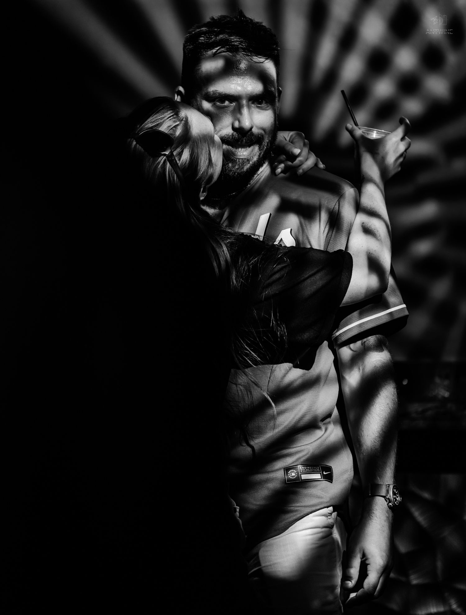 Black and white portrait of a bearded man with dramatic shadow patterns across his body in artistic lighting.
