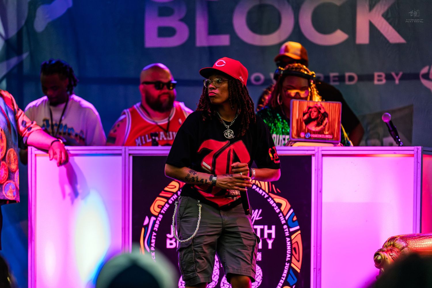 Performer in red jersey on stage at Juneteenth Block Party event under colorful purple stage lights.
