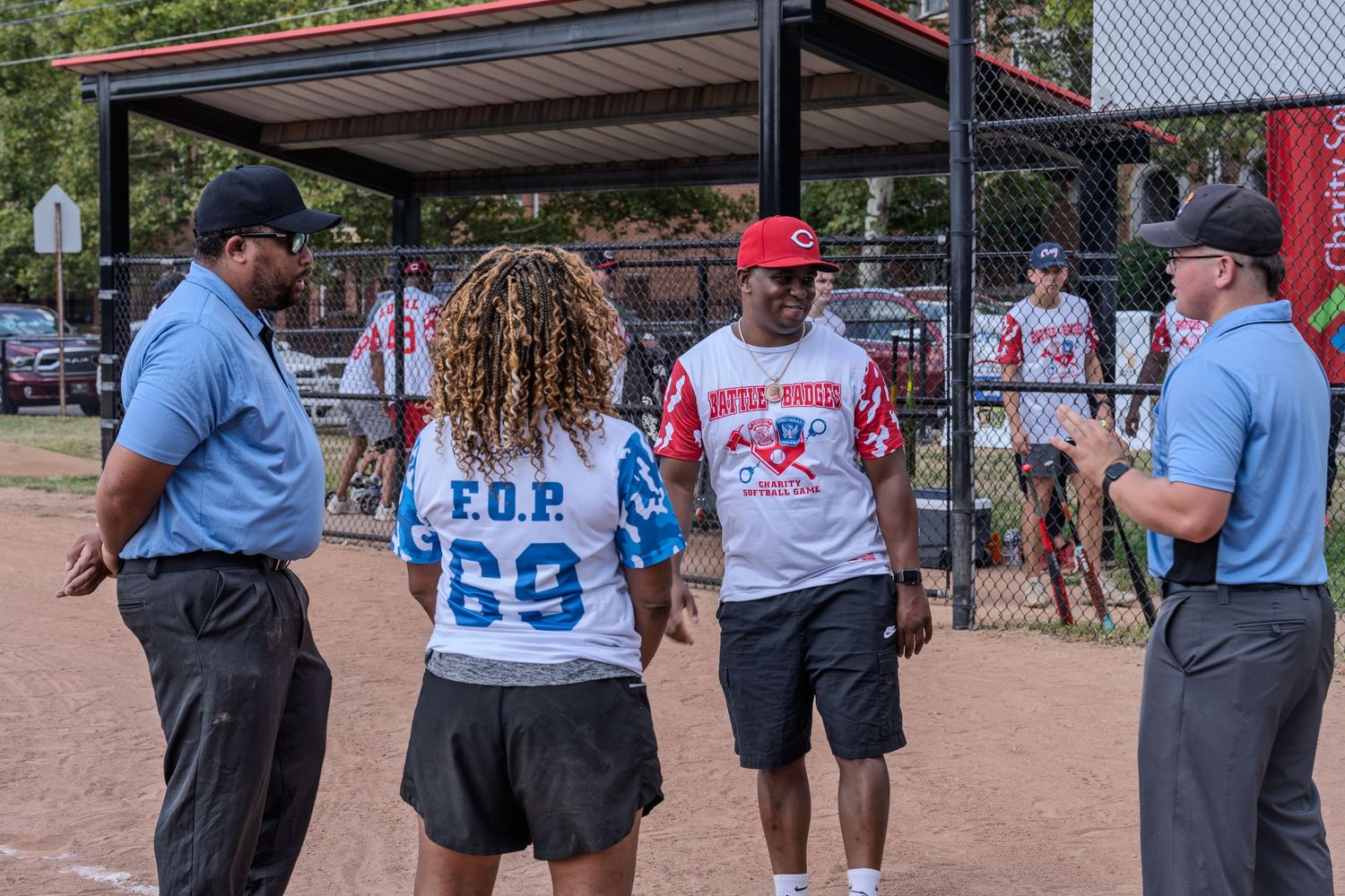 Baseball players and umpires gather near the dugout fence before a game.