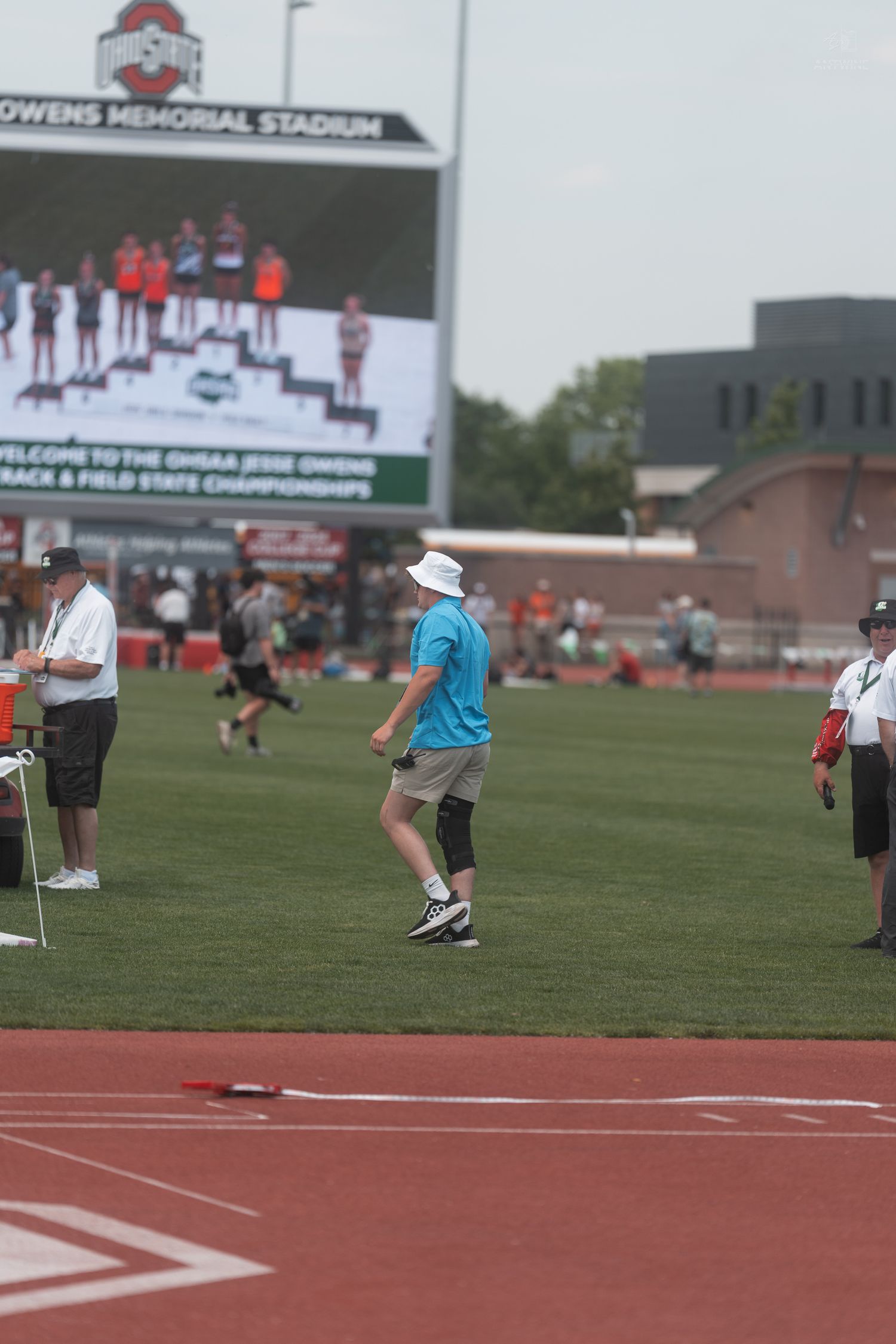 Official in blue shirt walks on track at OHSAA Jesse Owens Memorial Stadium during the Track and Field State Championships.