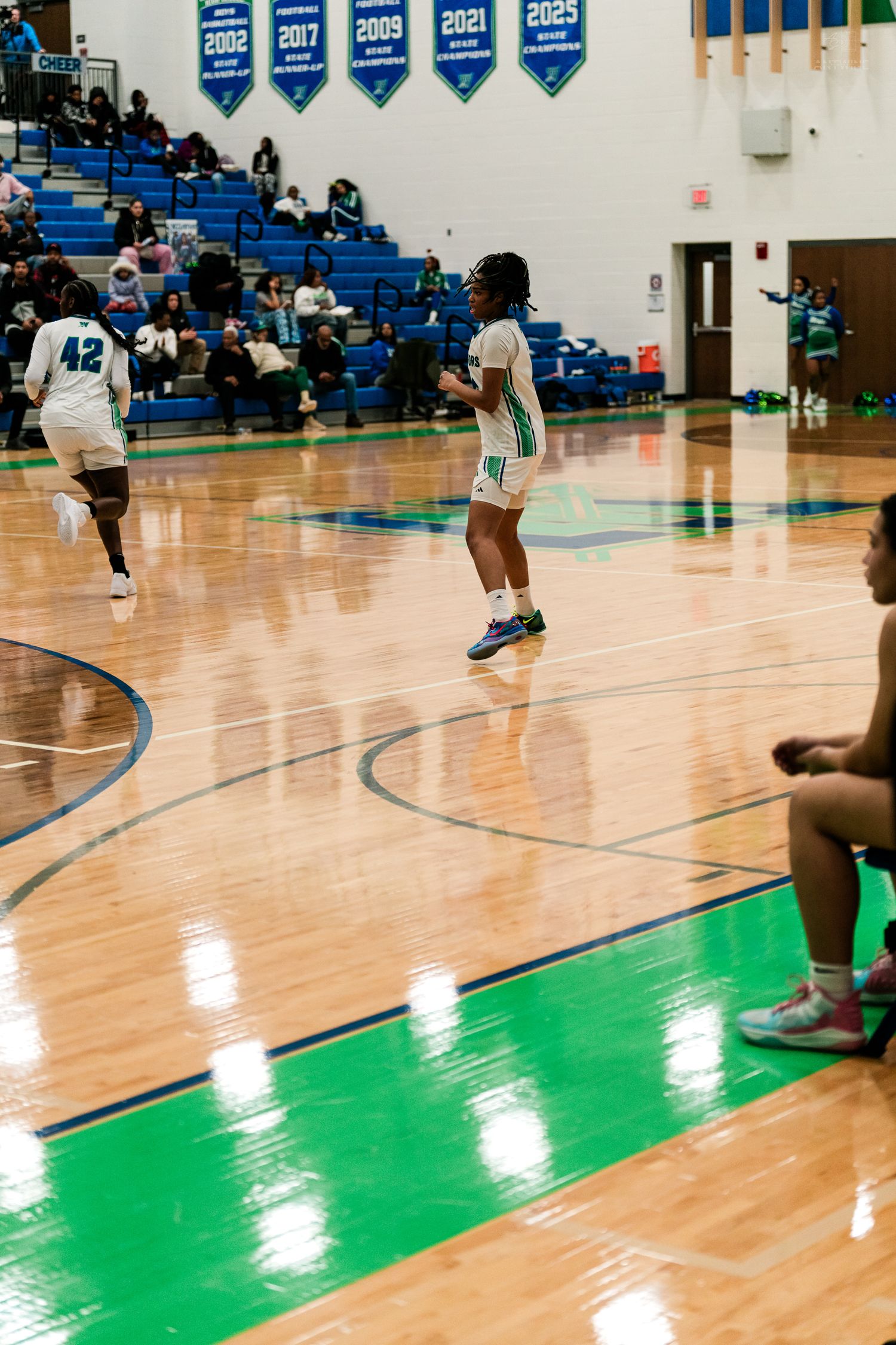 Warriors girls basketball players #42 and teammates set up on the court during a home game.