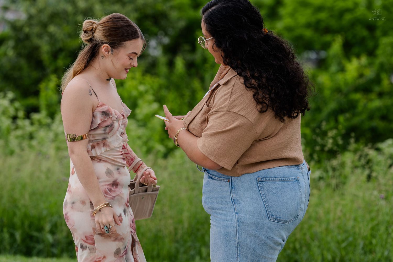 Two women sharing a joyful moment together in a lush green outdoor setting.