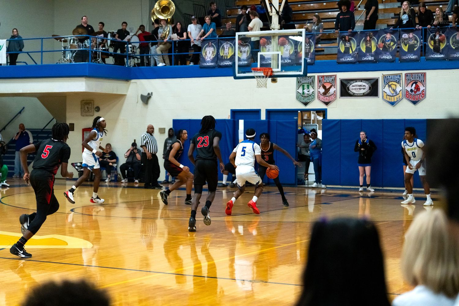 High school basketball players compete on court as fans fill the bleachers during an exciting game.