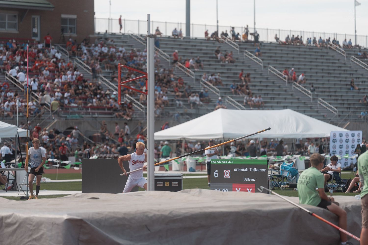 Javelin thrower competes at a packed outdoor track and field championship stadium event.
