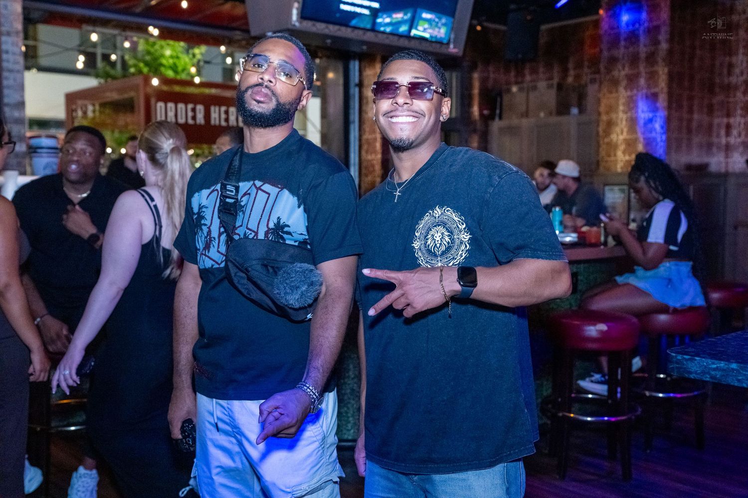 Two men in black t-shirts smiling and posing together at Stretch Bar.