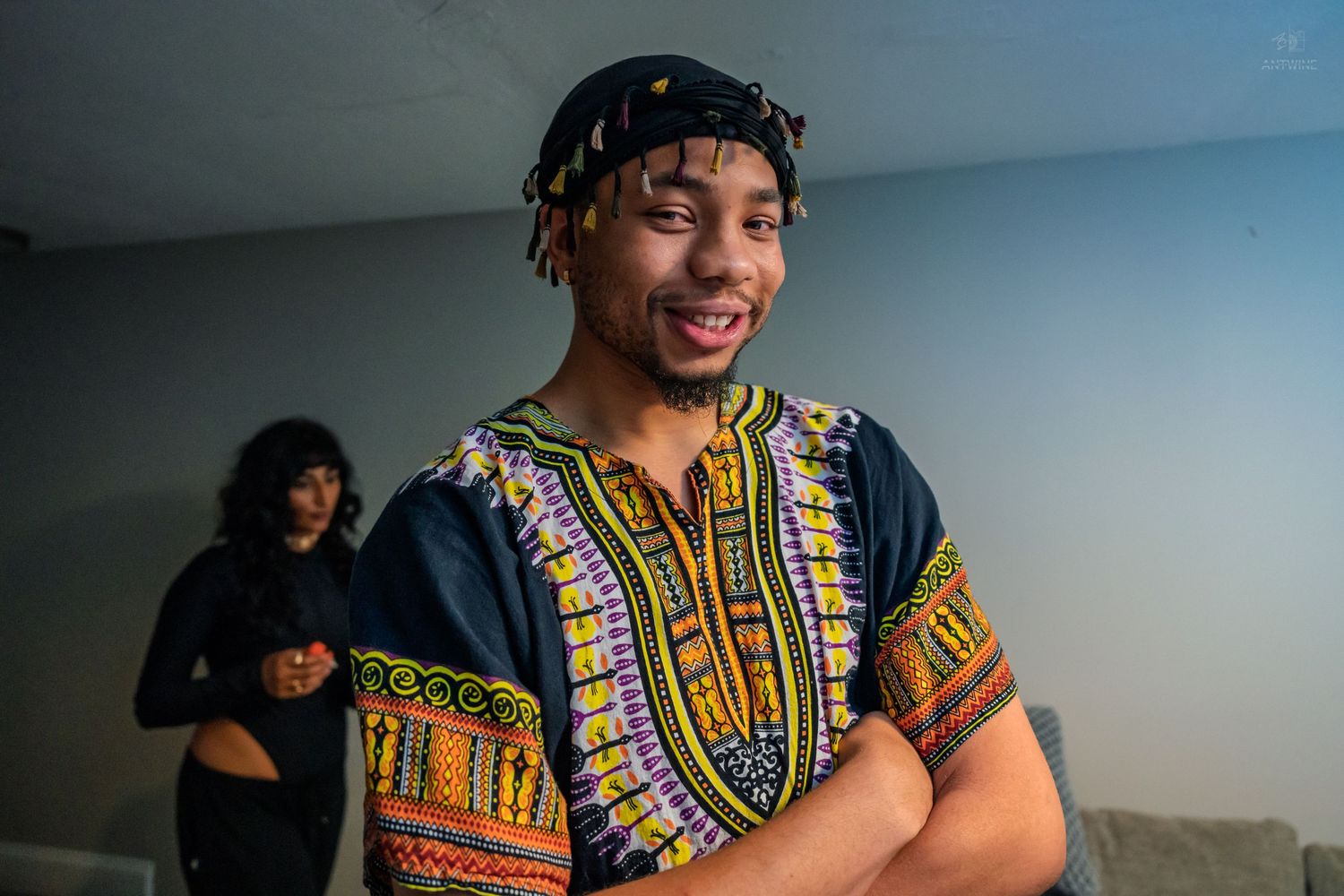 Smiling young man in colorful dashiki shirt posing at an indoor birthday celebration.