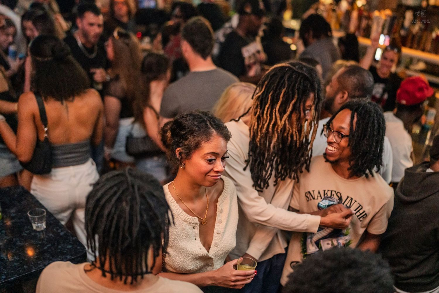 Friends laughing and bonding together at a crowded indoor nightlife event.