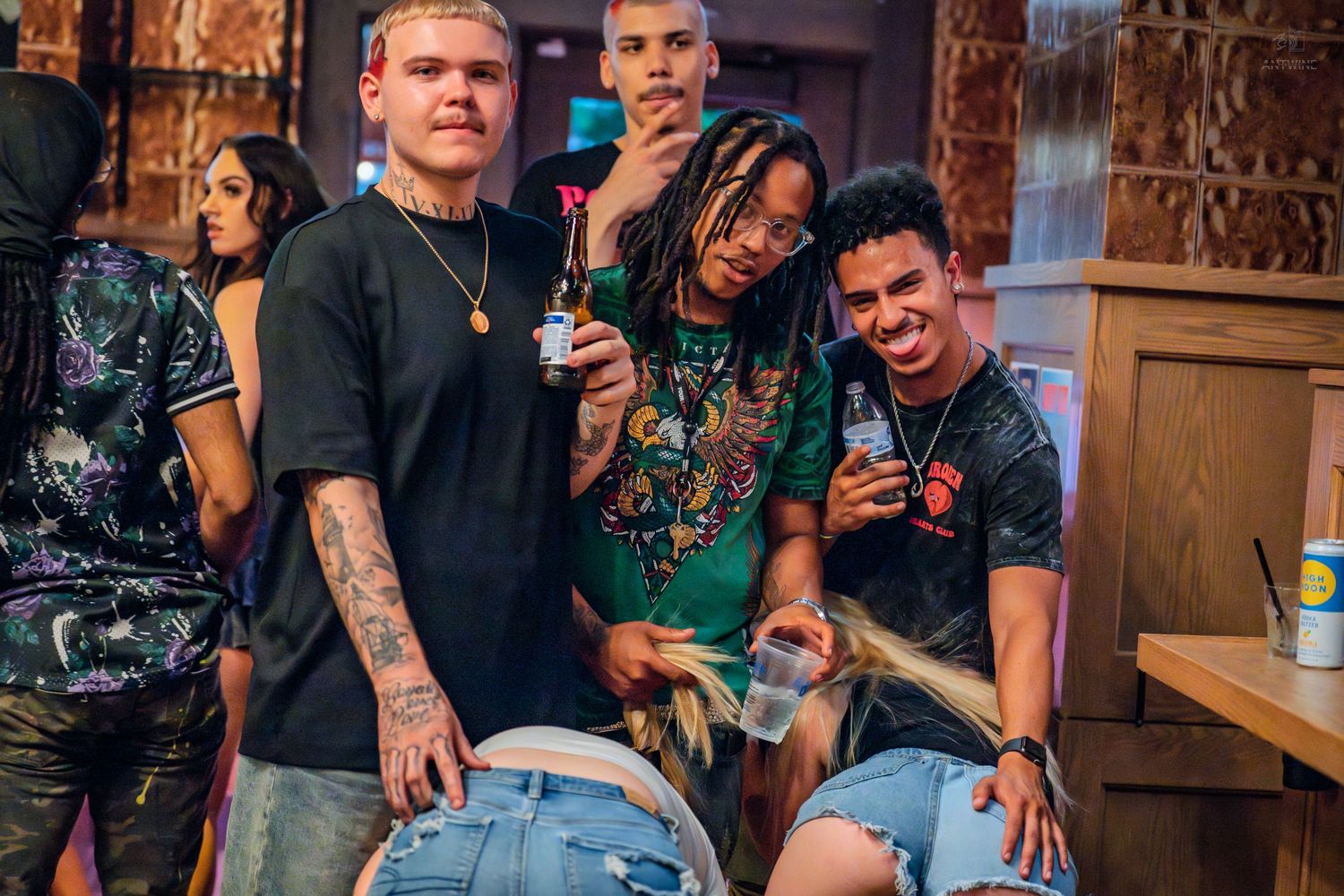 Group of young friends laughing and posing together at a lively indoor bar event.