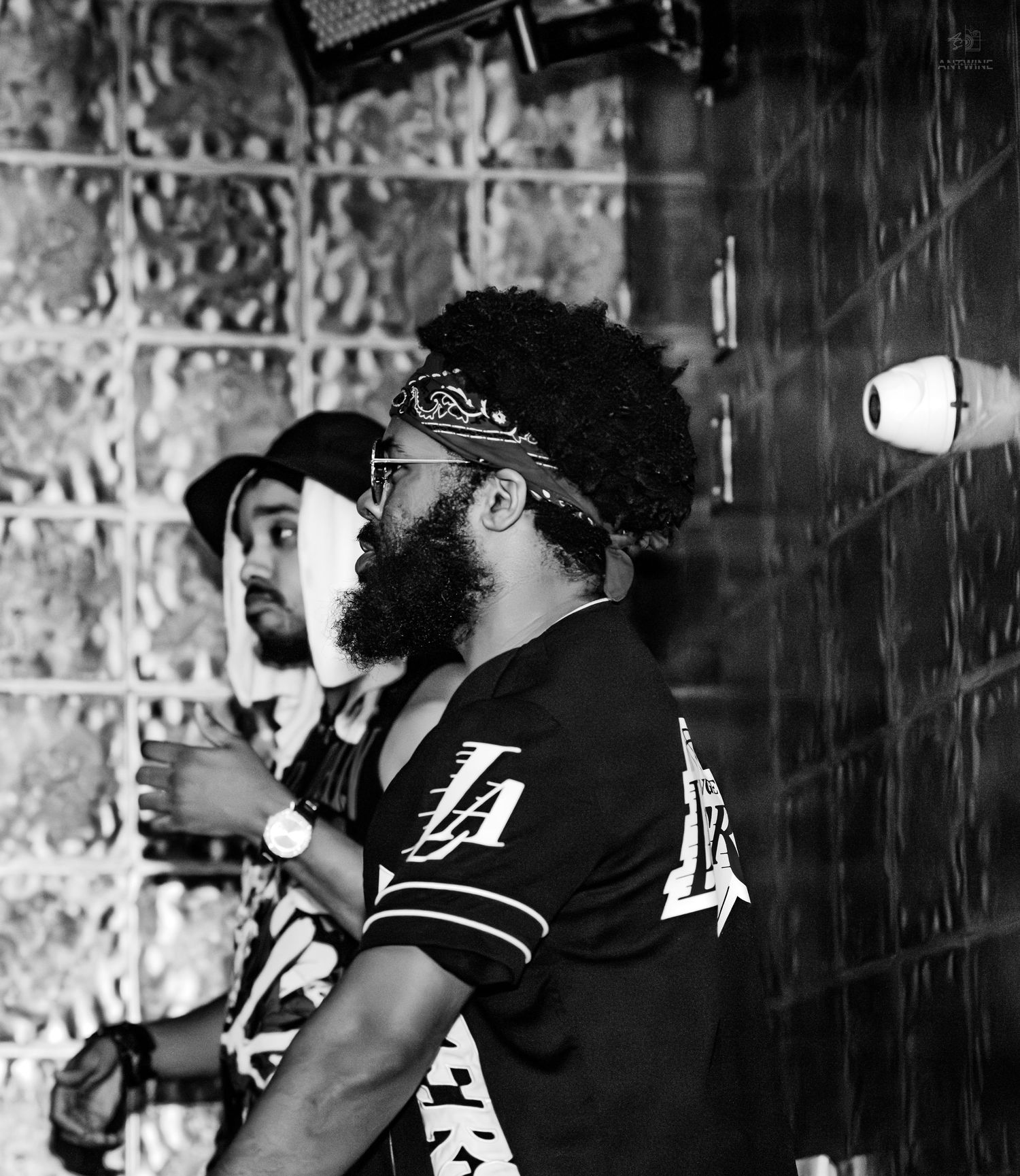 Two men in black and white photo standing at a bar wearing LA jerseys and bandanas.