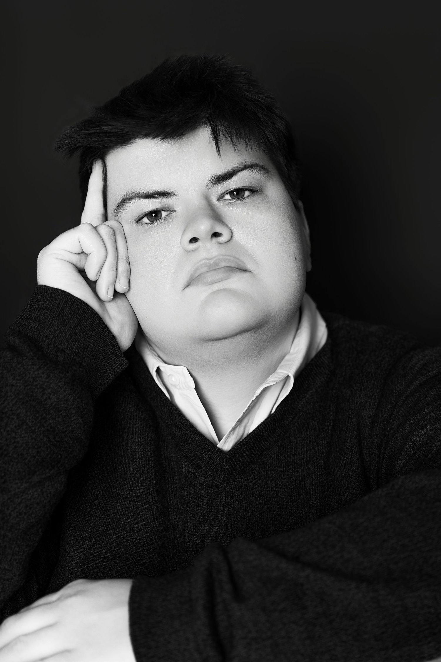 Black and white portrait of a young person resting head on hand with thoughtful expression.