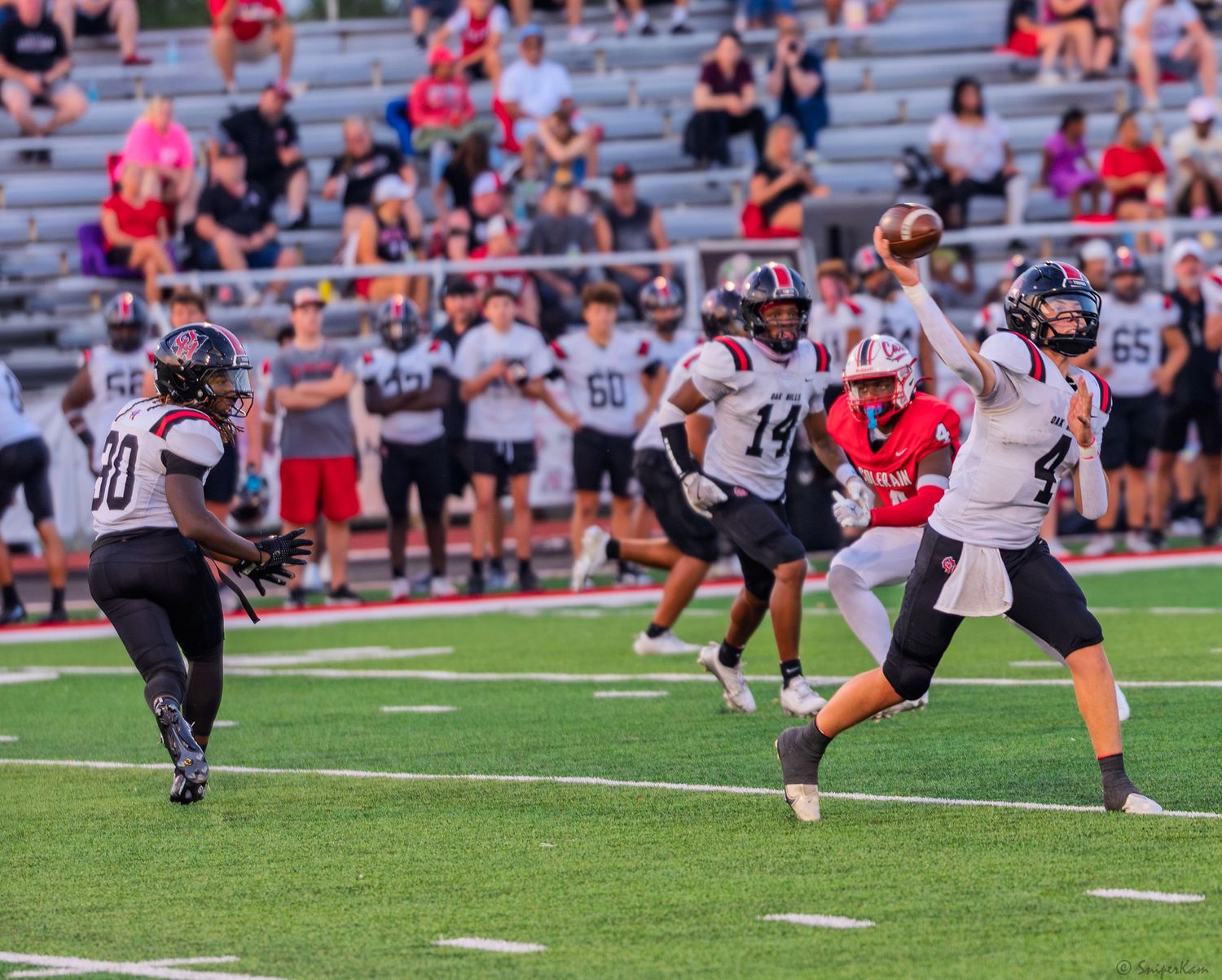 High school quarterback releases a pass under pressure during a competitive Friday night football game.