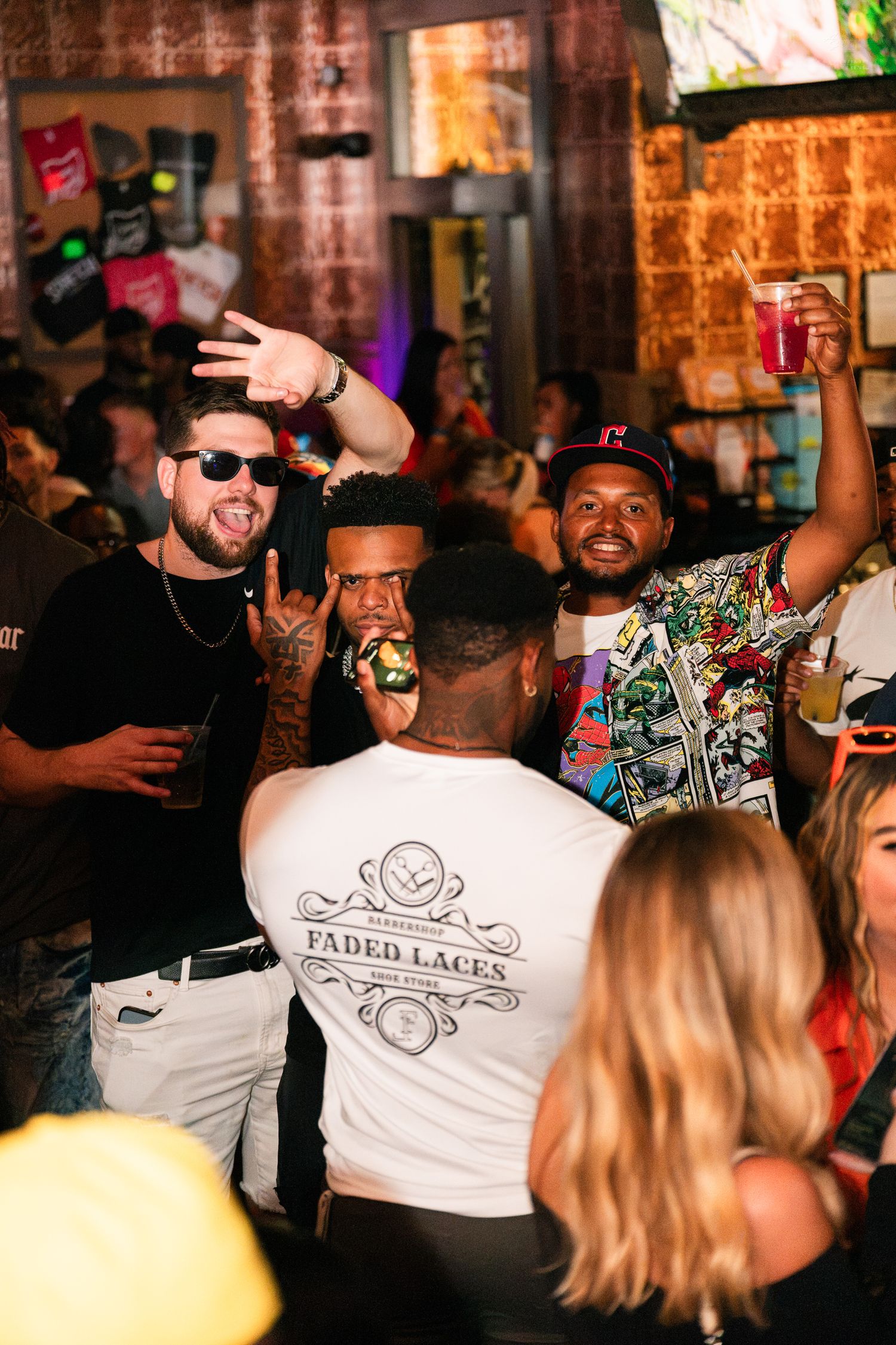 Friends celebrating with drinks at a vibrant crowded bar party.
