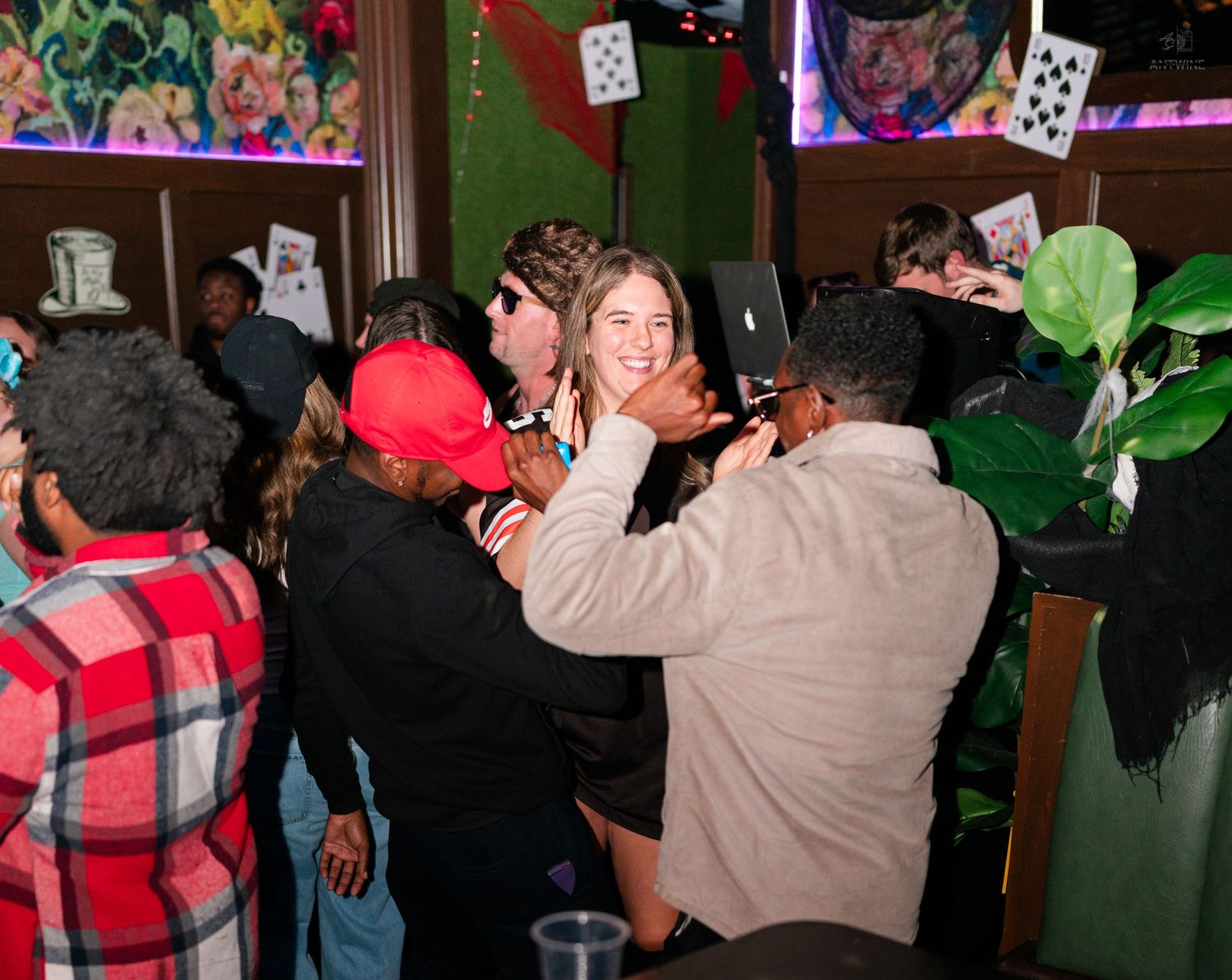 Friends laughing and dancing together at a colorful Halloween bar celebration.