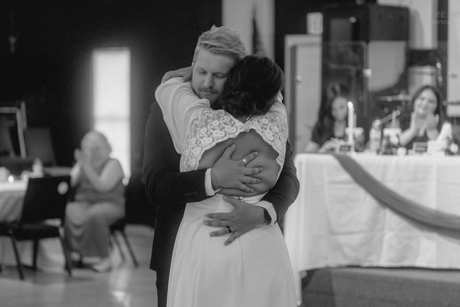 Bride and groom share an intimate first dance embrace in black and white wedding reception photo.