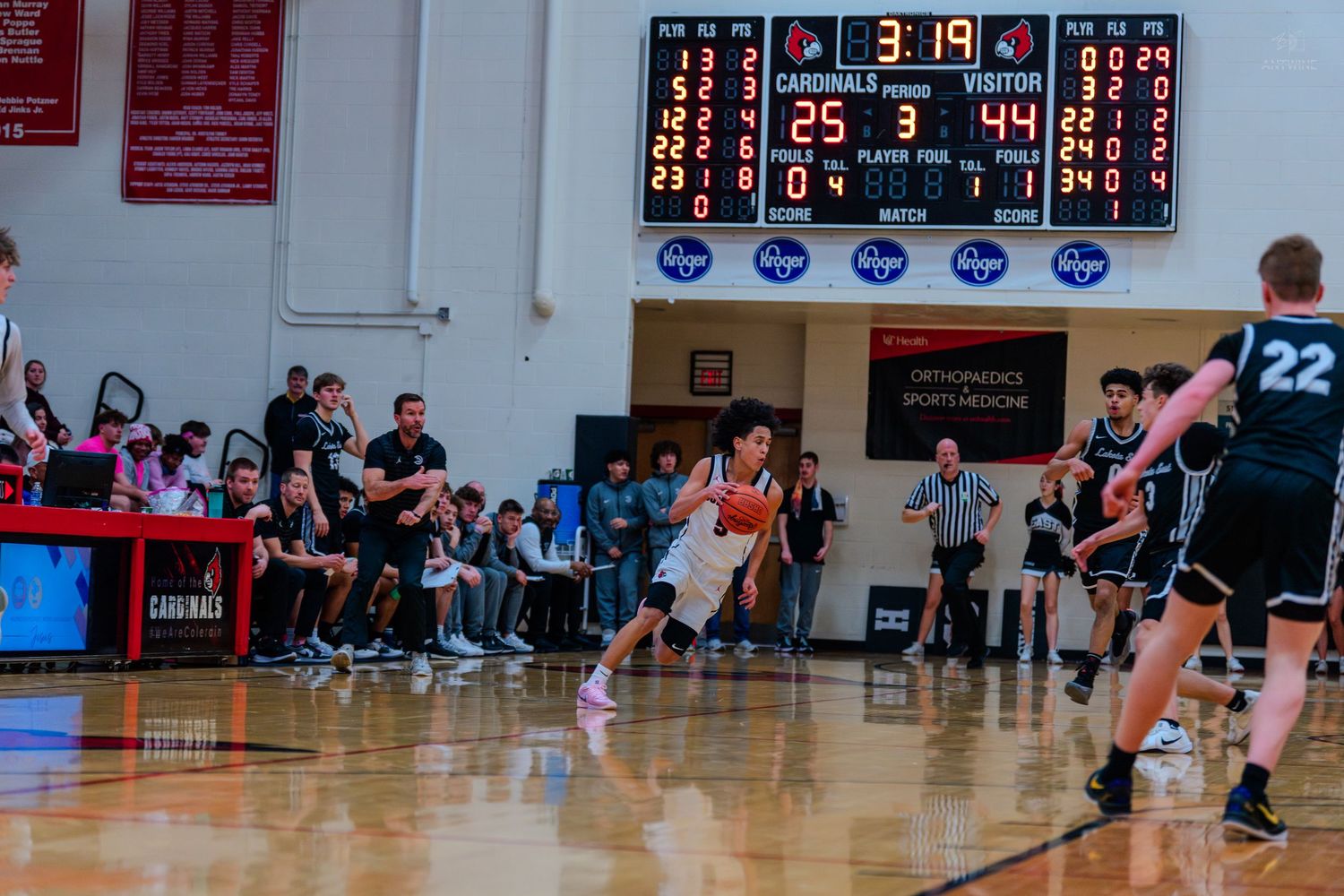 Colerain Cardinals basketball player handles ball with 3:19 on scoreboard during home game.