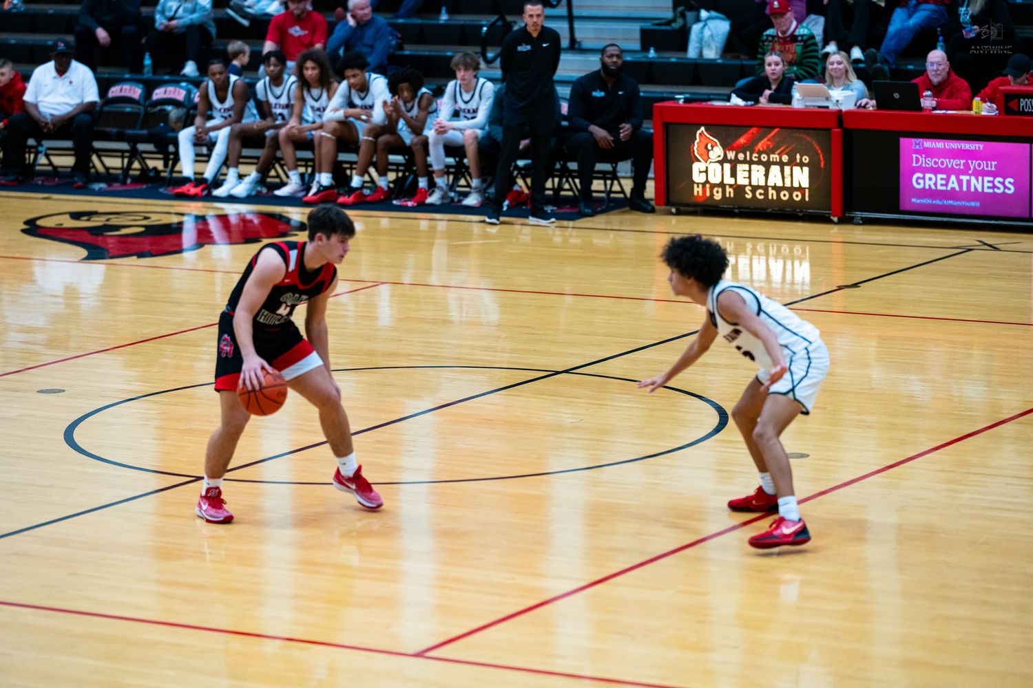 Two players face off near Colerain High School banner during intense basketball game.