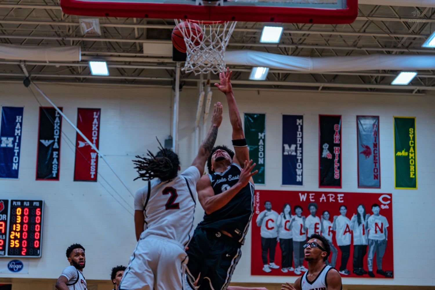 Basketball player #2 attempts block during high school gym game.