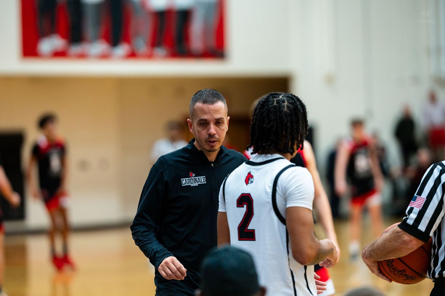 Basketball coach talks to player number 2 during timeout with referee nearby.