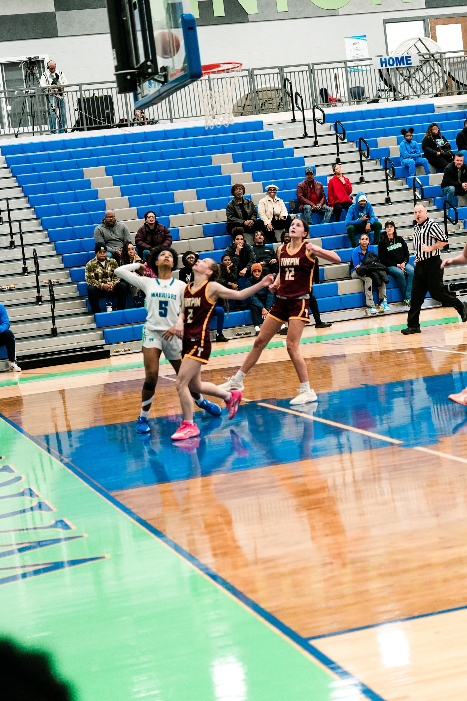 Female basketball players compete for position under the basket during a high school girls basketball game.