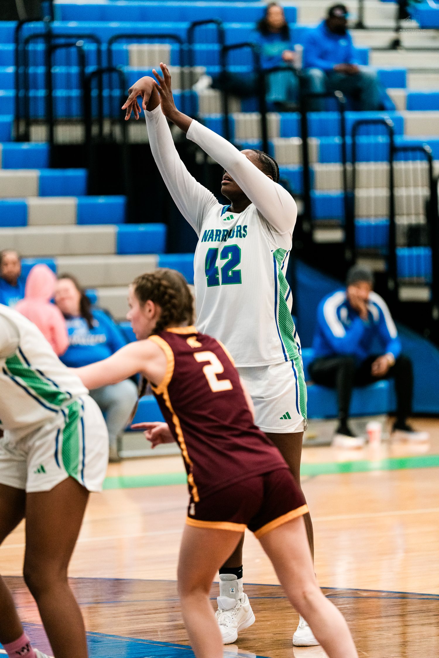 Player #42 in white Harbors jersey shoots a basketball during a girls high school basketball game.