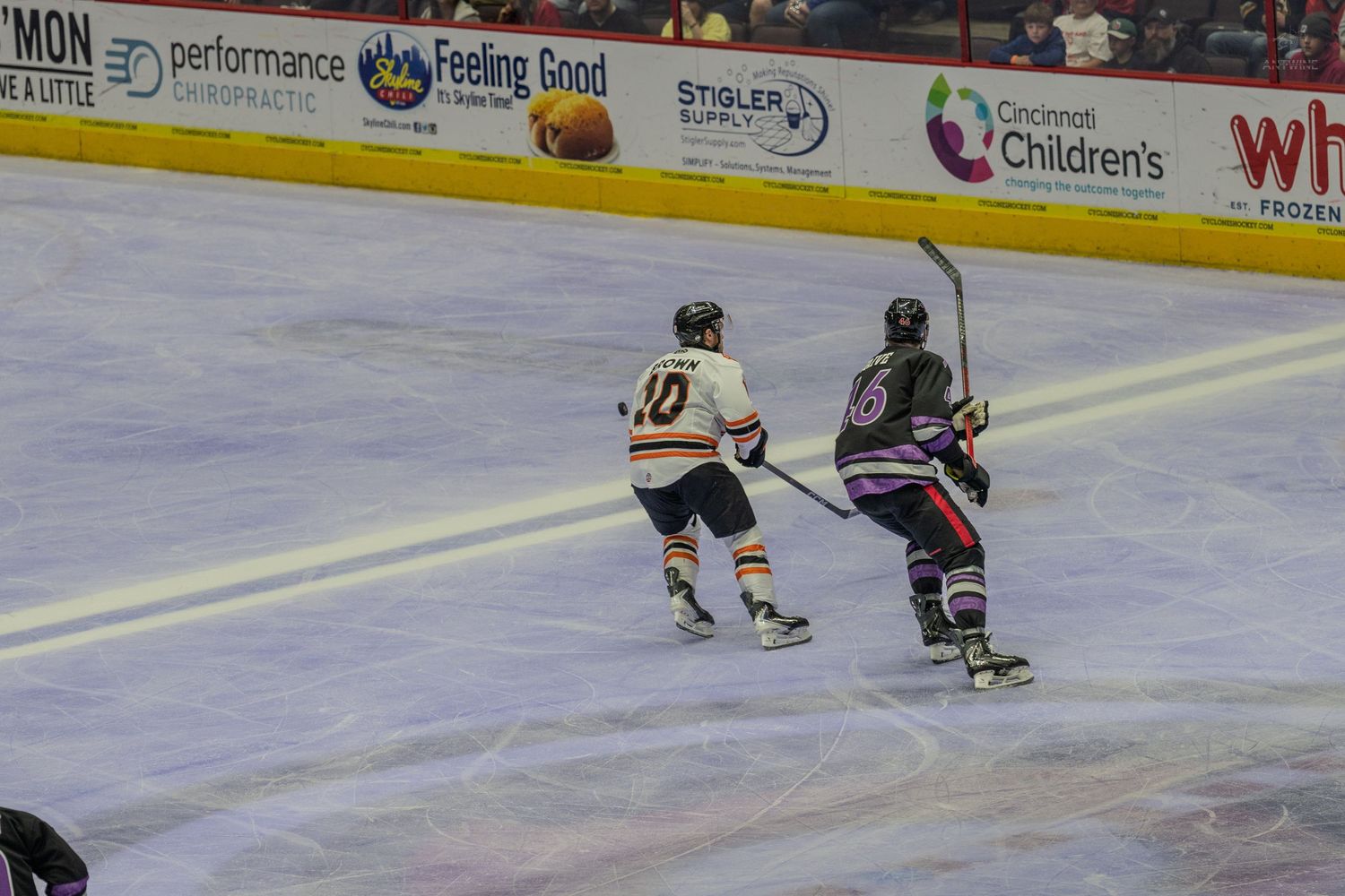 Two ice hockey players battle for the puck along the boards during a game.