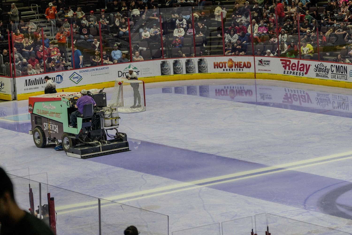 Zamboni ice resurfacing machine cleaning the rink during a hockey game intermission.