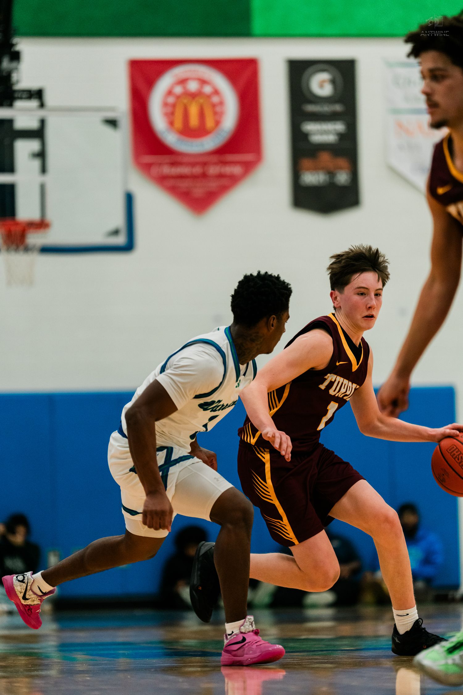 Turpin player #1 dribbles past Winton Woods defender during high school basketball game in blue gymnasium.
