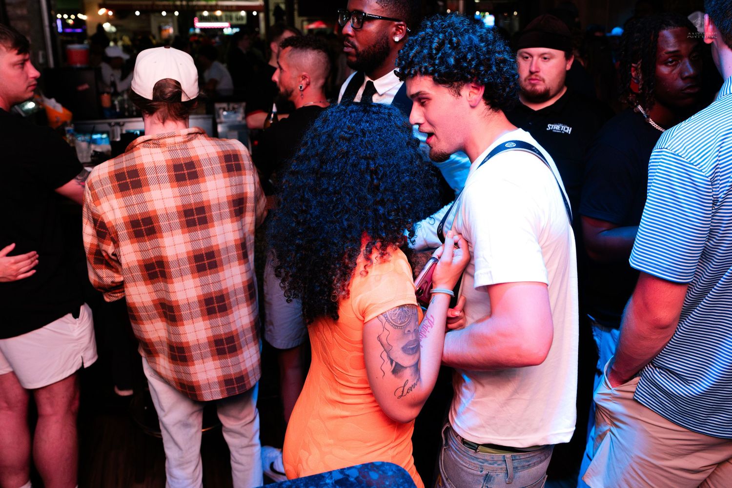 Couple dancing closely together at a vibrant indoor nightclub party.