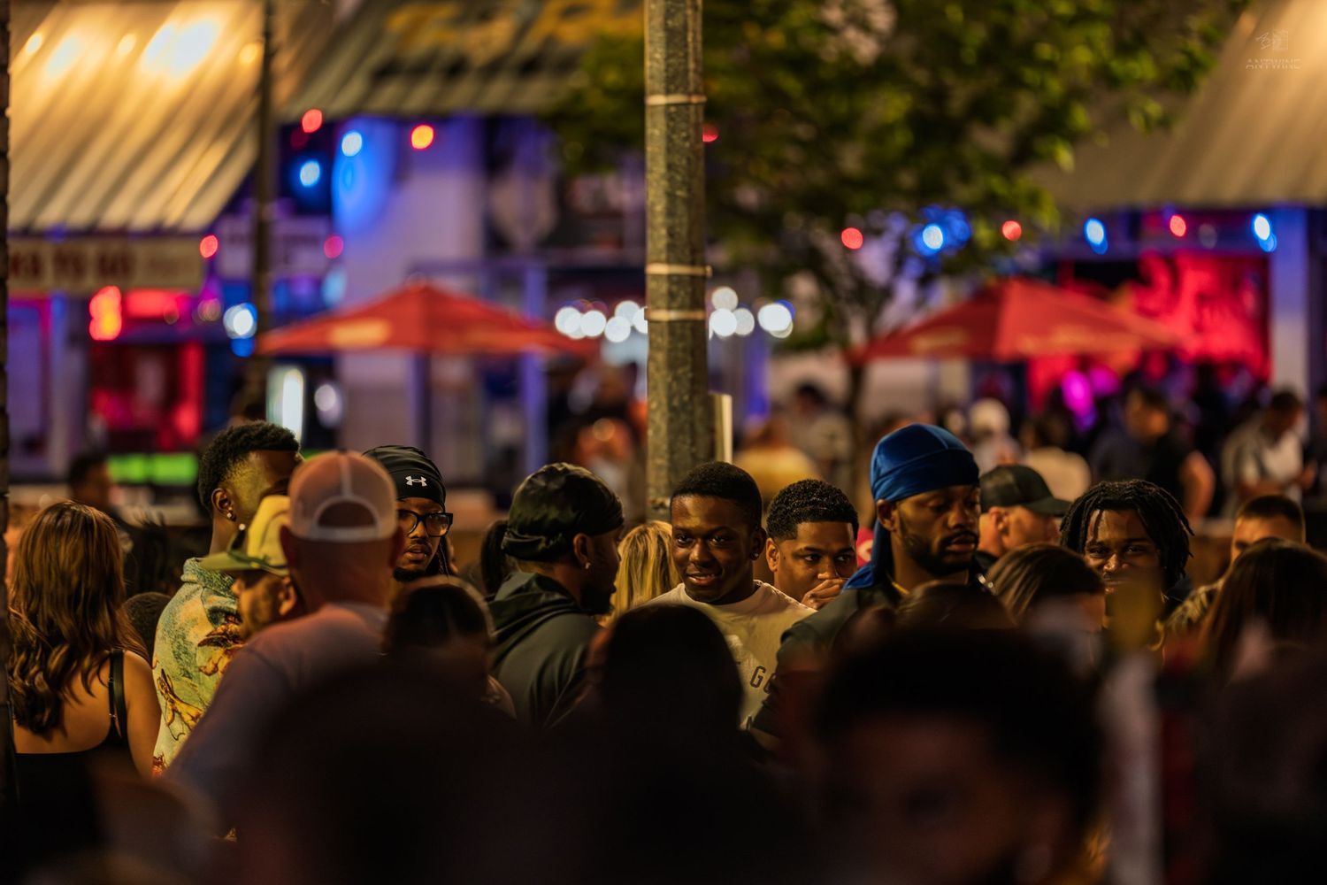 A large crowd of people gather outdoors at a vibrant nighttime street festival.